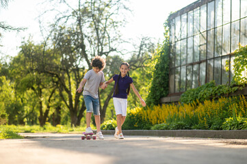 Obraz premium Cheerful girl teaching a boy to skateboard