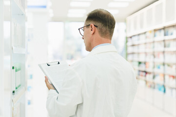 Back view shot of male middle-aged mature druggist chemist checking medical prescription on...