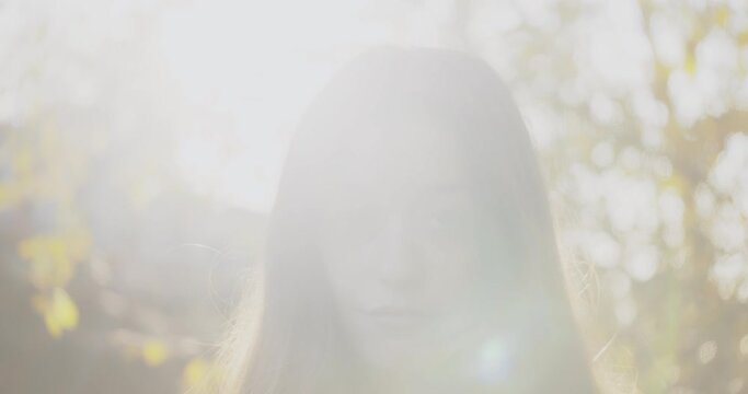 Portrait of attractive female in forestry area against very bright sunshine. Face reveal shot