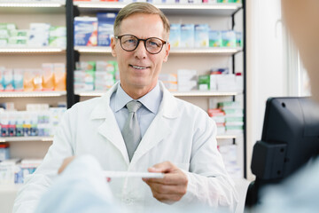 Cropped client customer buyer in pharmacy giving male caucasian chemist pharmacist druggist medical...