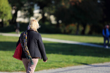 Kobieta z torebką spaceruje w parku we Wrocławiu.