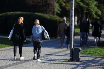 Kobiety z torbami spacerują w parku.