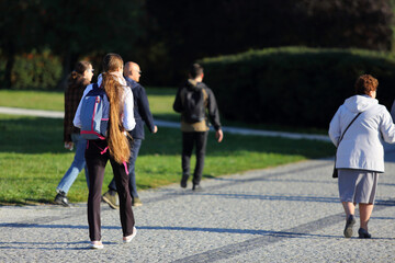 Kobieta z plecakiem i z długimi, pięknymi włosami spaceruje w parku we Wrocławiu.