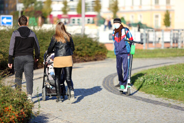 Para młodych ludzi z dzieckiem w wózku spaceruje chodnikiem, alejką we Wrocławiu. - obrazy, fototapety, plakaty