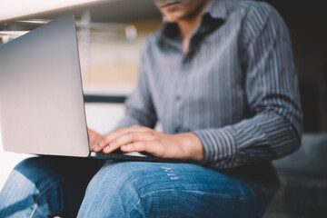 Asian millennial guy using laptop on stairs