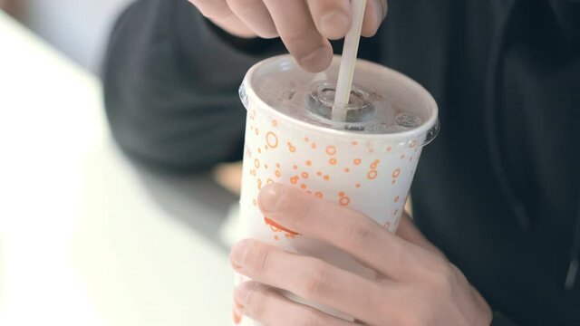Man student drinks Coca cola at McDonalds fast food restaurant. Unhealthy nutrition, snacks, junk food. 