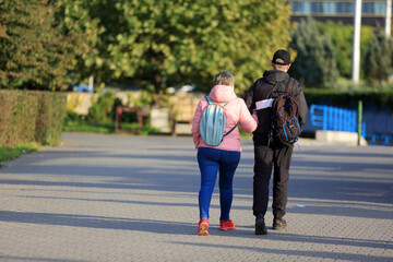 Para ludzi, kobieta i mężczyzna z plecakami spaceruje w parku we Wrocławiu.	