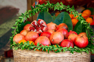 Basket with juicy ripe pomegranate fruits and oranges prepared for squeezing juice in a street cafe