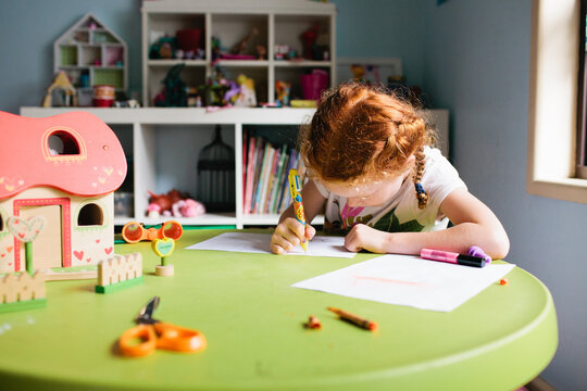 Young girl drawing at a table in a bedroom
