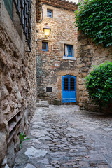 Fototapeta na wymiar View of a flowered street in the medieval village of Peratallada, in Girona, Catalonia, Spain