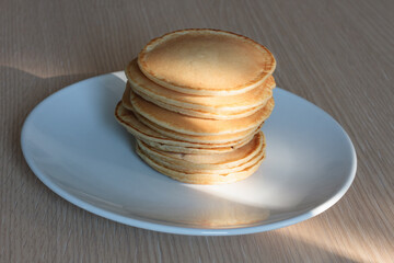 Pile of pancakes on a white dish illuminated by a beam of light - 479806644