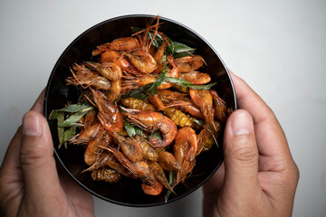 hand holding a dish of shrimp