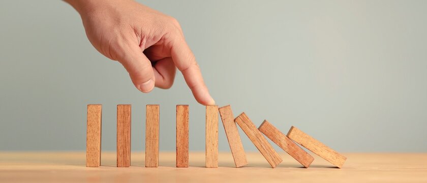 Risk and Strategy in Business, Hand Stopping wooden block domino business crisis effect or risk protection concept, business solution and intervention