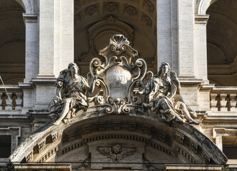 Detail of the façade of the Church of Santissima Annunziata with a pair of angels indicating a central cartouche with the Latin inscription: 