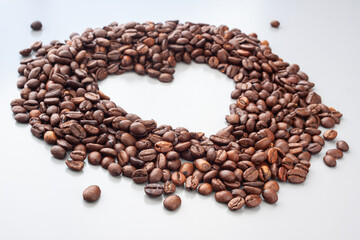 Coffee beans in a heart shape on the gray background. Blured background. Coffee lovers