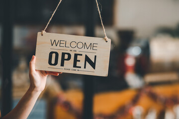 Welcome. Open. barista, waitress woman turning open sign board on glass door in modern cafe coffee...