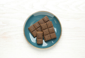 Blue plate with delicious and healthy hematogen on white wooden table, top view