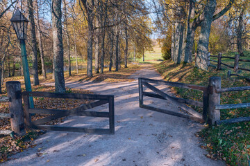 a narrow dirt path leading through an open wooden gate into a field. Mikhailovskoe. Pushkin mountains. Pskov. Russia - 479810831