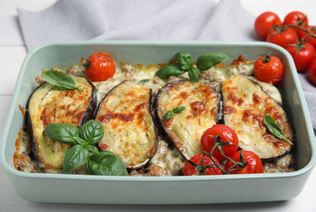 Delicious eggplant lasagna in baking dish on white wooden table