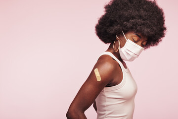 African woman with a mask and vaccination bandage