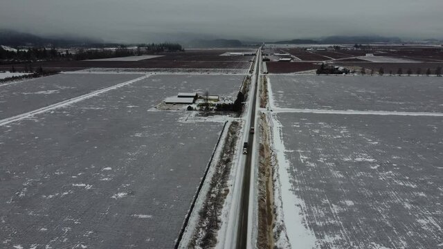 Tractor Trailers Crossing Winter Road Farmland