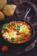Fried eggs on pan with buns. Shakshouka is Maghrebi dish of eggs poached in a sauce of tomatoes, olive oil, peppers, onion and garlic