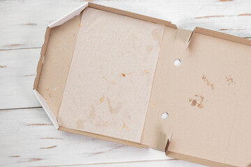 Empty open pizza box. White wooden background. Eaten pizza. Top view.