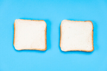 Two pieces of white toast on a blue background. Food concept.