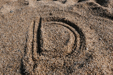 English alphabet. Sand on the beach. The letter D