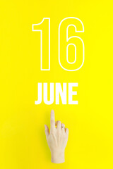 June 16th. Day 16 of month, Calendar date.Hand finger pointing at a calendar date on yellow background.Summer month, day of the year concept.