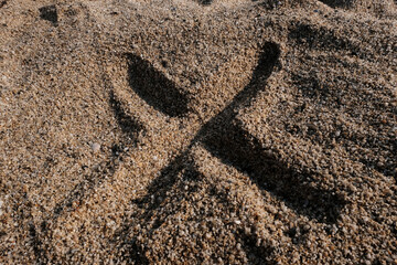 English alphabet. Sand on the beach. The letter X