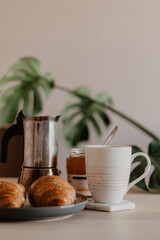 French breakfast with croissants, coffee and monstera in the background