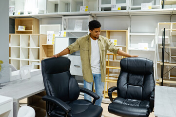 Man choosing office armchairs in furniture store