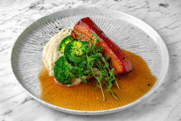 Baked pork with mashed potatoes and boiled broccoli. in a festive plate on a marble background. Restaurant banquet menu.