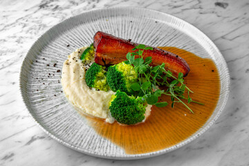 Baked pork with mashed potatoes and boiled broccoli. in a festive plate on a marble background. Restaurant banquet menu.