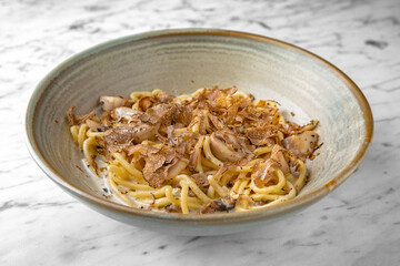 Pasta with truffle and cheese in a festive plate on a marble background. Restaurant banquet menu.
