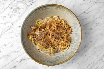 Pasta with truffle and cheese in a festive plate on a marble background. Restaurant banquet menu.