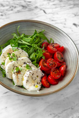 Caprese with mozzarella cherry tomatoes, arugula and pesto in a festive plate on a marble background. Restaurant banquet menu.