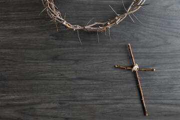 crown of thorns with simple wood cross on a dark wood background with copy space