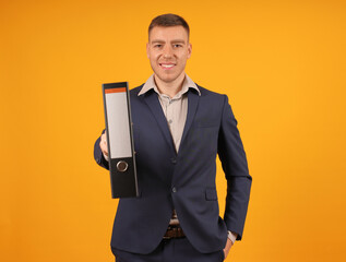 a man in a suit confidently holds a folder with a place for text in his hands on a yellow background