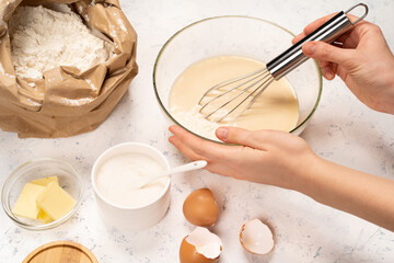 the process of making dough for pancakes with ingredients on a light table, eggs and flour are whipped with a mixer