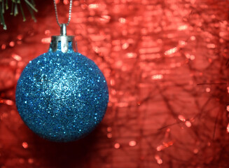 New Year and Christmas, blue ball hanging on a Christmas tree on a red shining background, greeting card