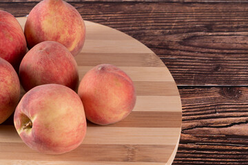 Tasty peaches (Prunus persica, in Latin), on wooden board, on rustic wooden table. Selective focus.