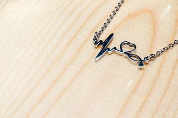 pendant cardiogram, heart, stethoscope on a chain on a wooden background, with copy space