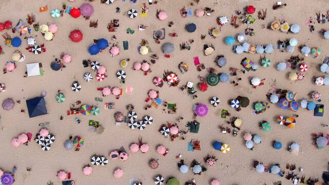 Top down aerial view of colourful sun umbrellas and people relaxing on a summer day at famous Copacabana Beach in Rio de Janeiro, Brazil.