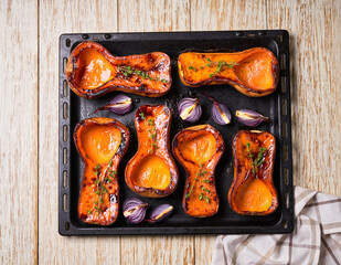 roasted butternut squash with rosemary  on a white wooden table, top view.