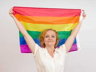 smiling woman holding rainbow flag above her head, white background