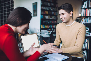 Male and female college students discussing project in library