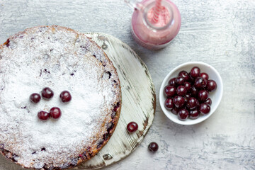 Homemade cherry pie and red cherry smoothie and sprinkled with berries on a gray table, close-up. Summer breakfast