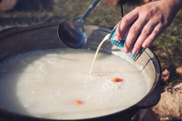 Sweet rice porridge with dried apricots in a large cauldron over a fire in the camp.